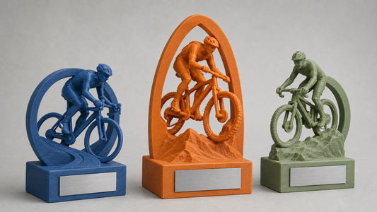 Tre trofei personalizzati in PLA per gare di ciclismo, con basi rettangolari, targhette Acciaio e layer della stampa 3D visibili